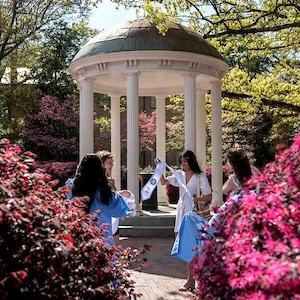 Students take cap and gown graduation portraits by the Old Well at U-N-C campus